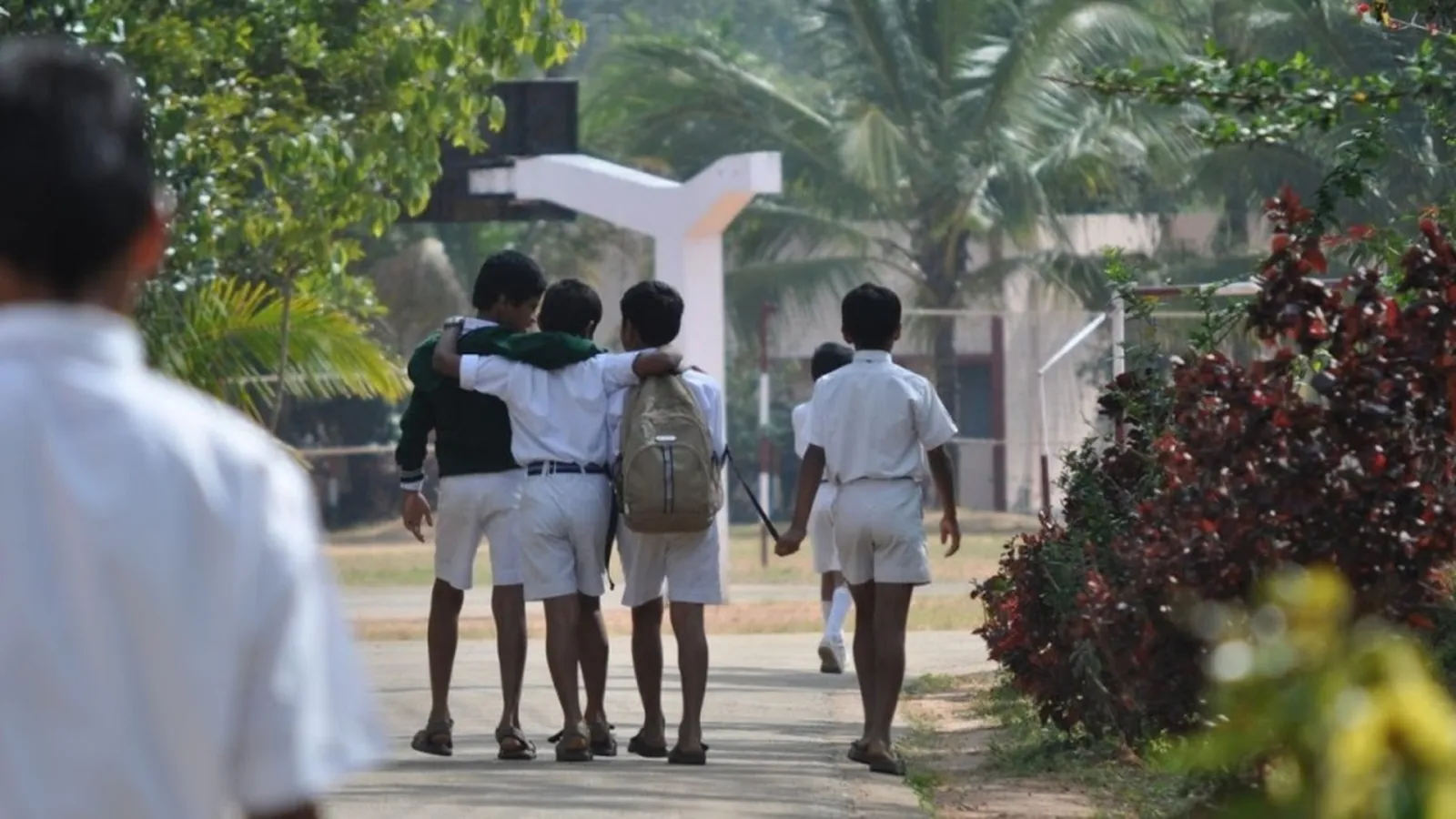 Students in uniform walking together along a campus path.