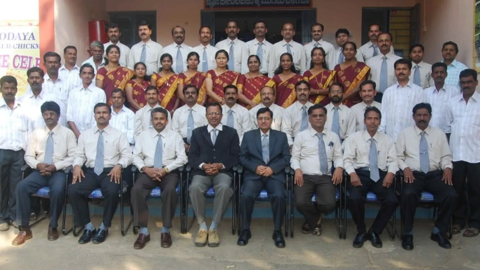 Teachers and staff photographed together in front of a school building.